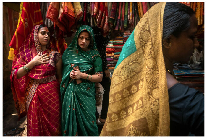 Women in colorful saris captured in a vibrant street market by Andrés Ramos, showcasing raw, unfiltered moments.