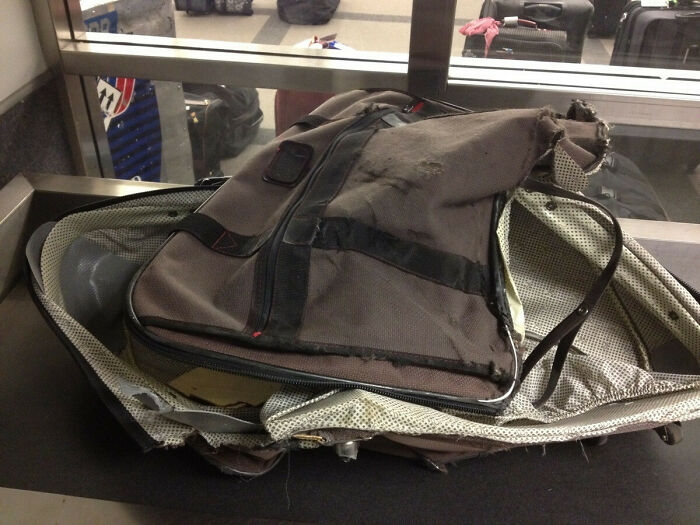 Damaged suitcase at airport check-in counter, showcasing an epic airline baggage fail.