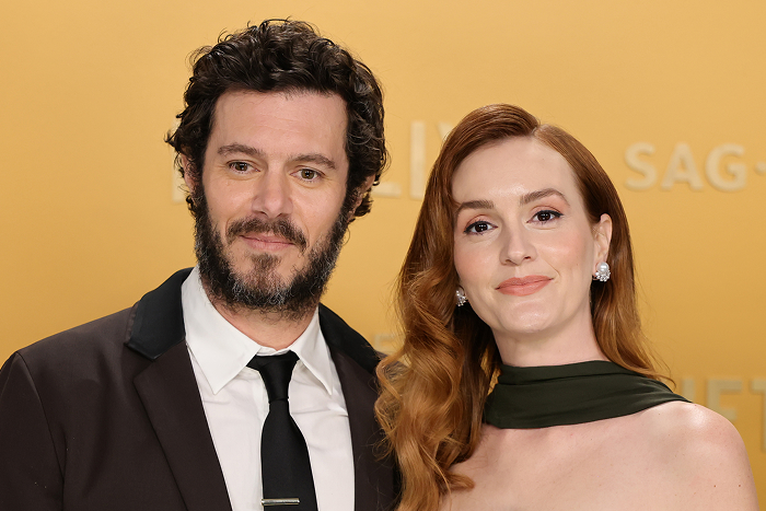 Leighton Meester and Adam Brody posing elegantly at a formal event with a golden backdrop.