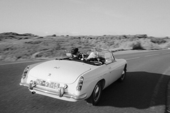 Vintage convertible driving on an open road, couple enjoying an engagement moment, one of the best photos of 2025.