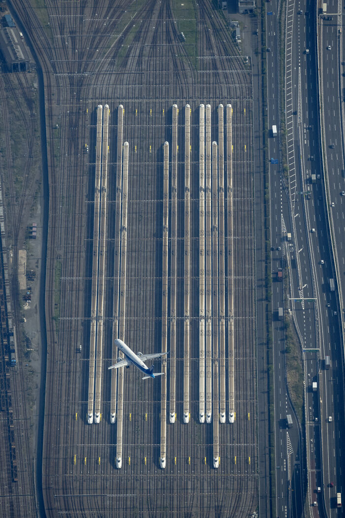 Aerial view of trains and a plane crossing tracks, showcasing stunning photography from the 2024 IPA.