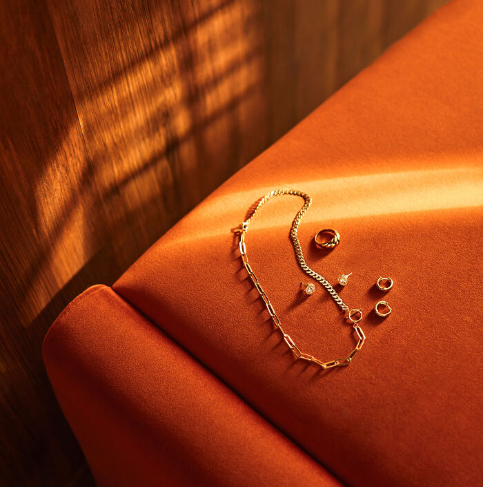 Golden jewelry arrangement on an orange fabric, showcasing stunning artistry from the 2024 IPA.