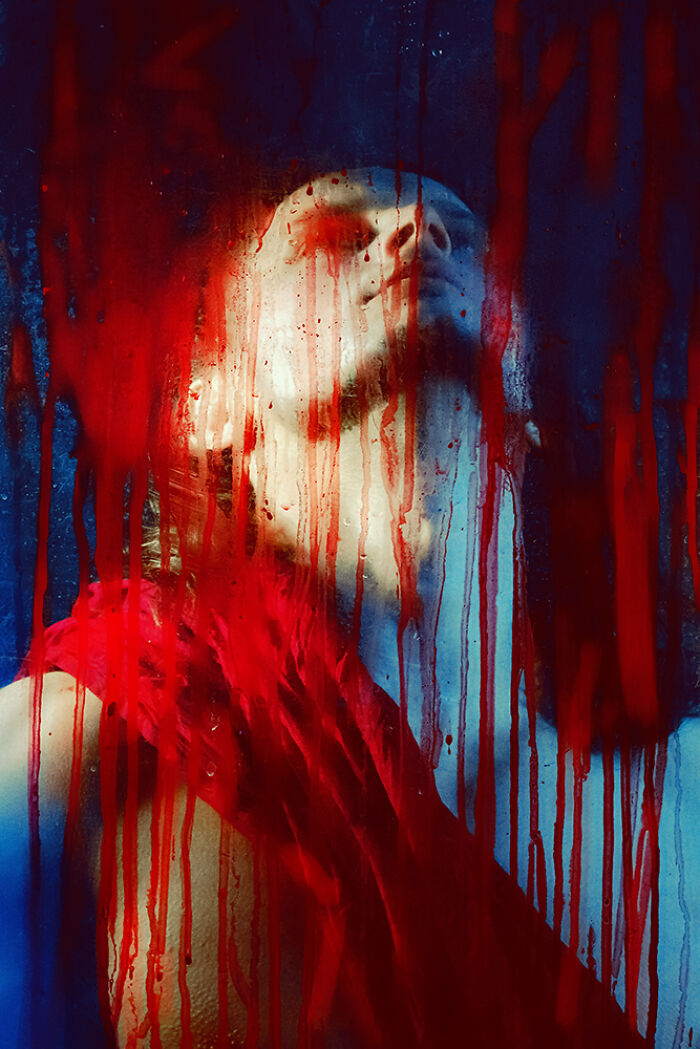 A person behind a glass streaked with vibrant red paint, capturing a stunning artistic moment from the 2024 IPA.