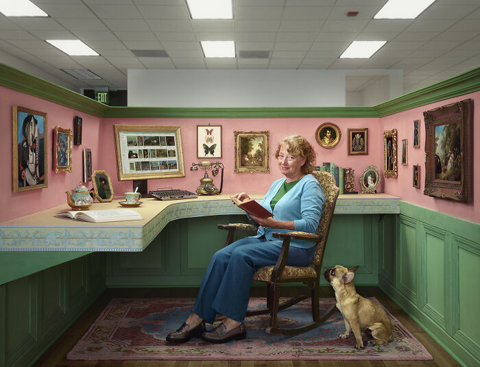 A woman reading in a pink and green art-filled office, with a dog looking up at her. Stunning photo from the 2024 IPA.