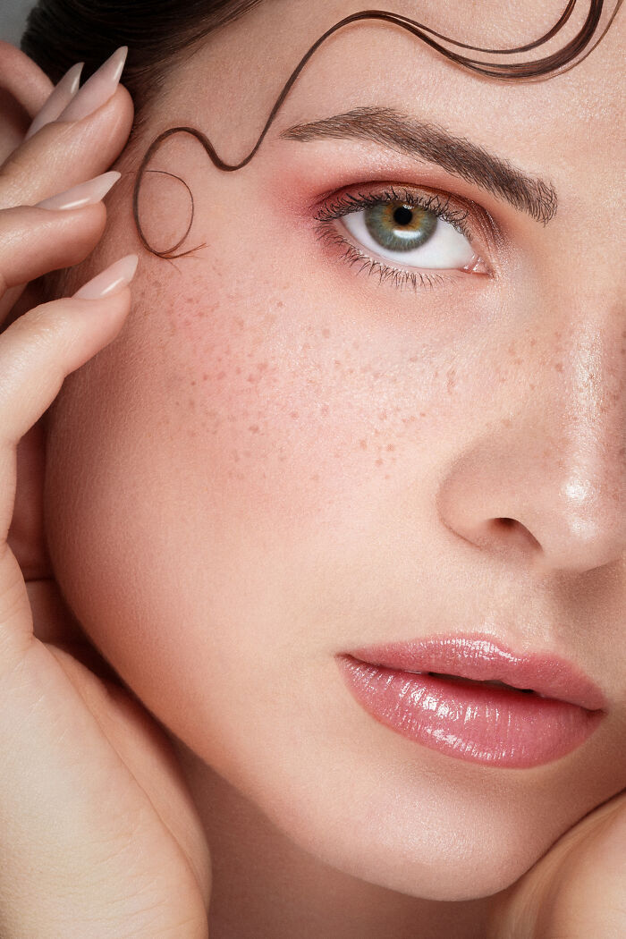 Close-up portrait of a woman with freckles and wavy hair, highlighting stunning photo techniques from IPA winners.