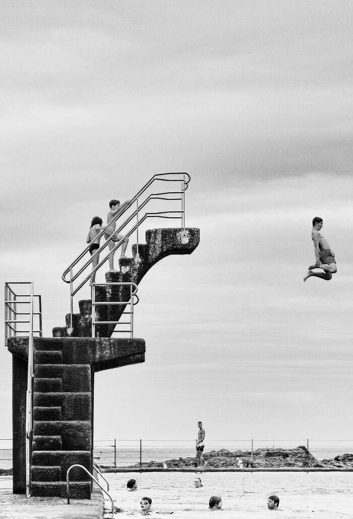 A diver jumps from a tall platform while others watch, capturing a stunning moment recognized at the 2024 IPA.