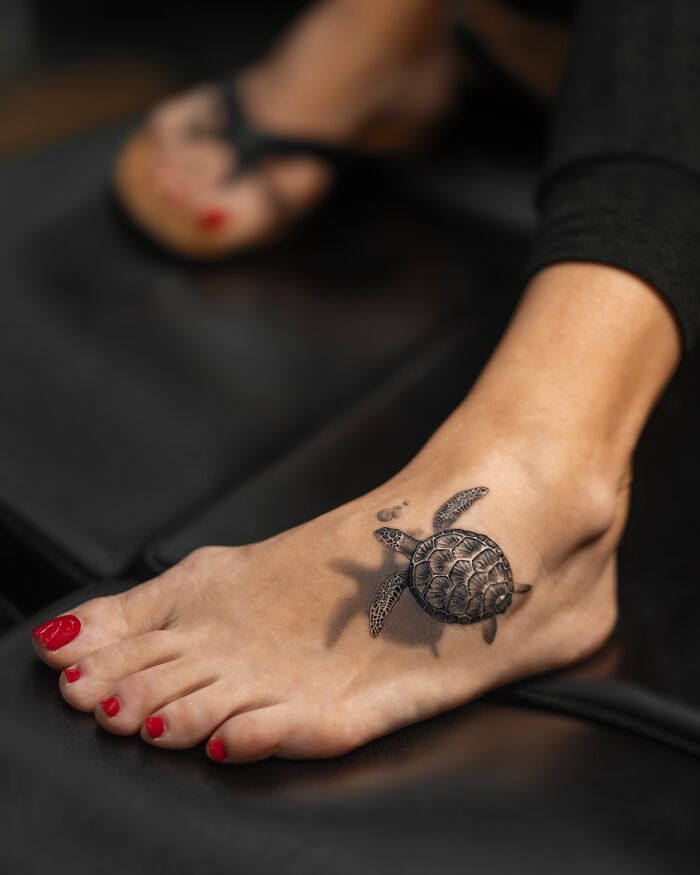 Lifelike turtle tattoo by Tatu Panda on a foot, with realistic detail and vibrant colors.