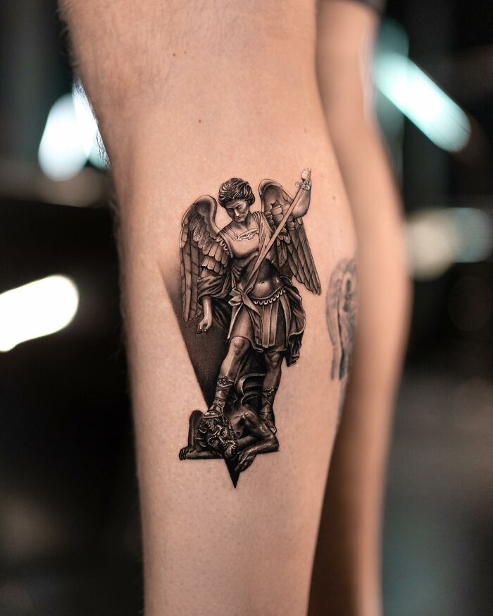 Detailed tattoo by Tatu Panda depicting an angel with a sword, showcasing lifelike artistry on a person's leg.