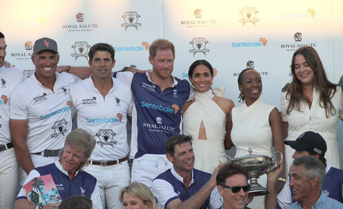 Royal Salute polo event with Harry and Meghan, posing with teammates and a trophy, featuring Sentebale branding.
