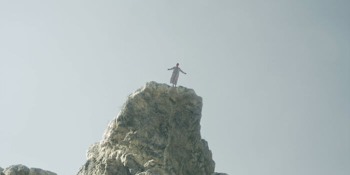 Person standing atop a rocky peak under a clear sky, symbolizing historical facts being questioned for accuracy.
