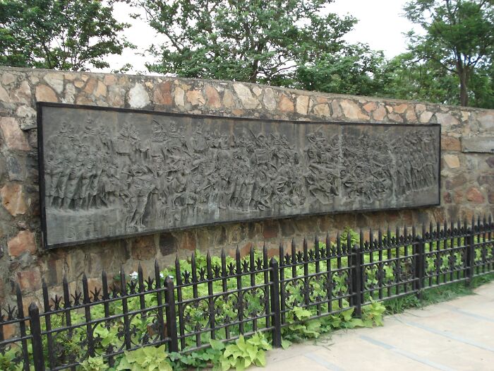 Historical turning points depicted on a detailed stone mural in a public outdoor setting.