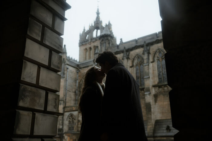 A couple shares a romantic moment in front of a historic cathedral, featured in the best engagement photos of 2025.