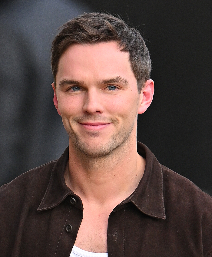 A person smiling, wearing a dark jacket and white shirt, highlighted in discussion about attractiveness off-screen.