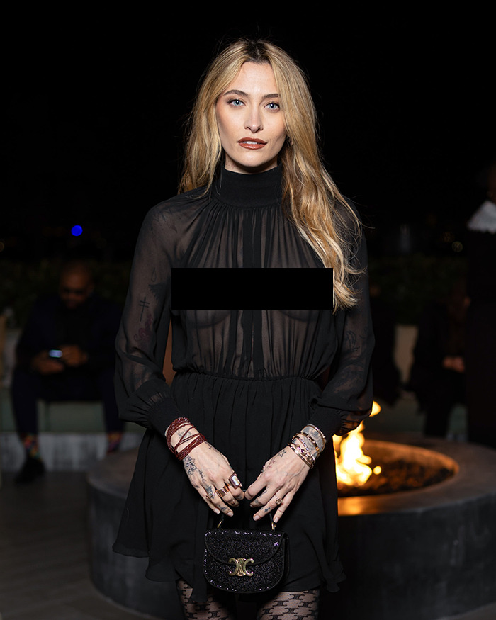 Celebrity wearing a revealing black sheer dress on the red carpet, sparking conversation and attention at a nighttime event.