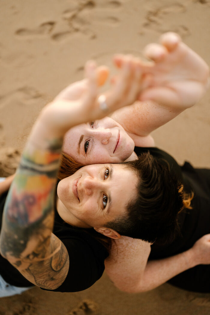 Couple embraces on the beach, smiling and capturing one of the best engagement photos of 2025.