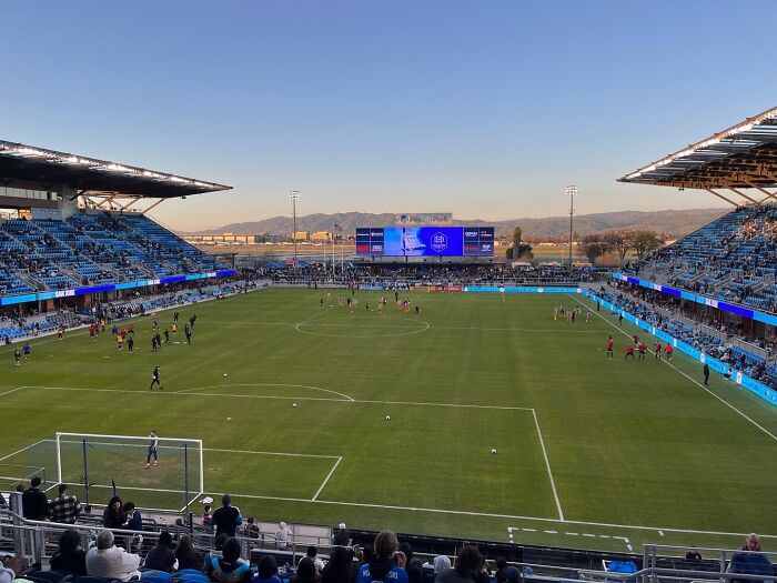 Soccer stadium with fans and players warming up on the field, one of the cathedrals of soccer at sunset.