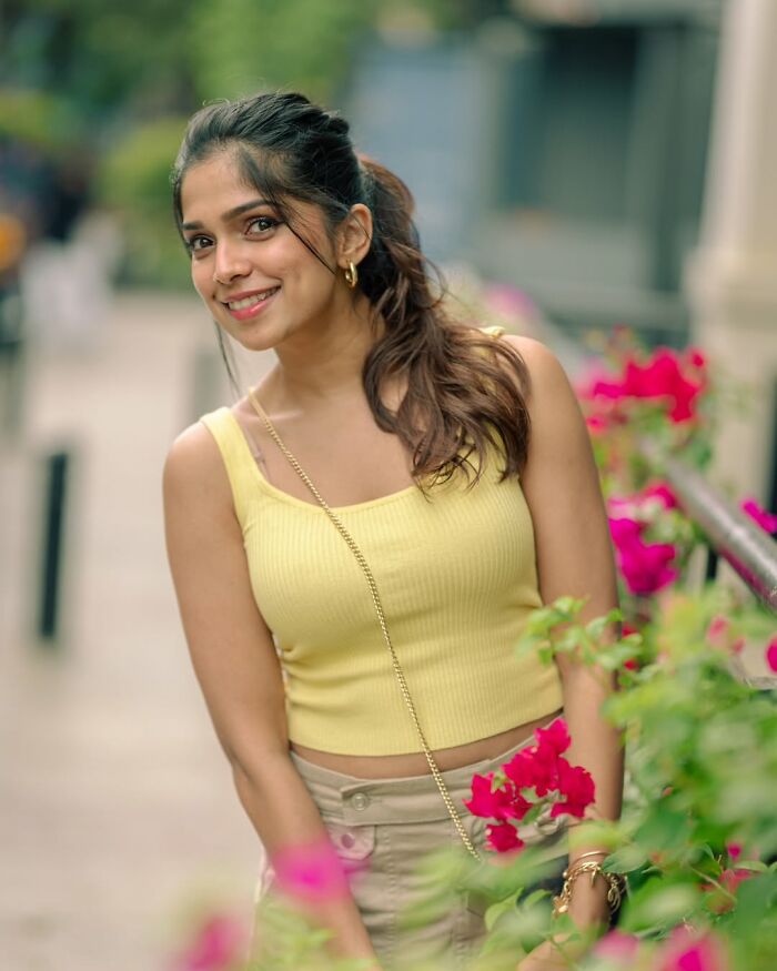 Indian photographer captures a smiling woman in a yellow top surrounded by vibrant flowers.