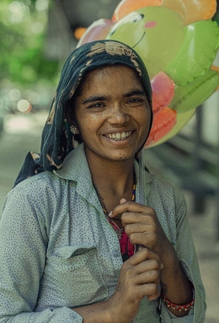 Smiling woman holding a colorful balloon, captured beautifully by an Indian photographer.