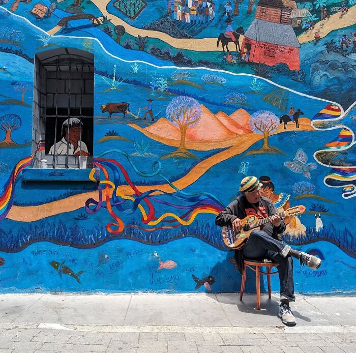 Musician plays guitar by vibrant mural, capturing San Francisco's essence.
