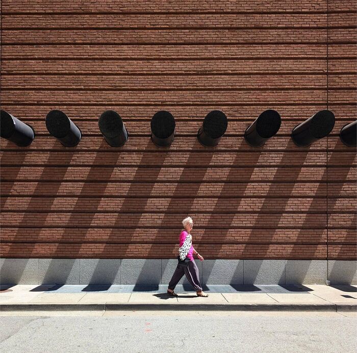 A person walks by a brick wall with shadows in San Francisco, captured by photographer Sage Akaboshi.