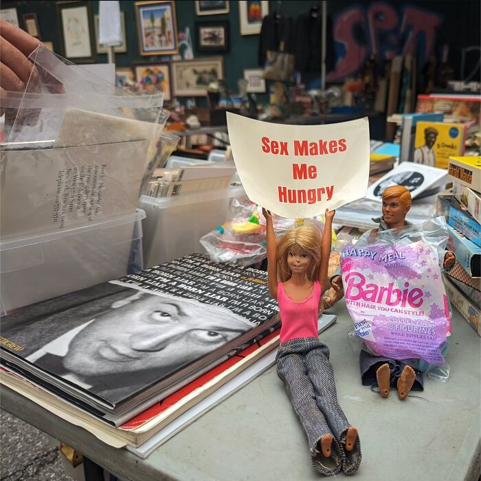 Barbie doll holding a sign in a quirky San Francisco scene, photographed by Sage Akaboshi.