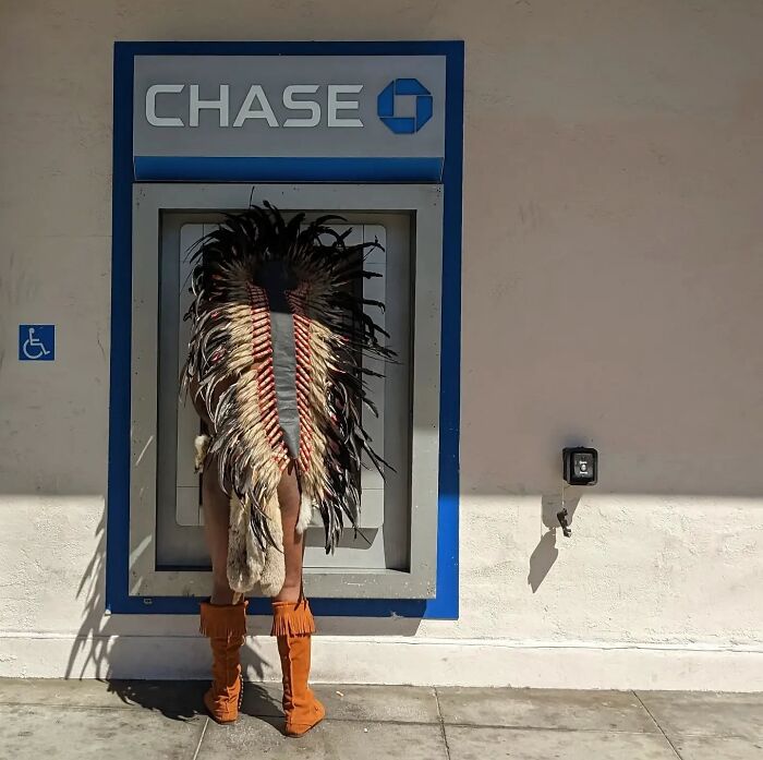 Person in a feathered headdress and boots at a Chase ATM, showcasing the essence of San Francisco's unique culture.
