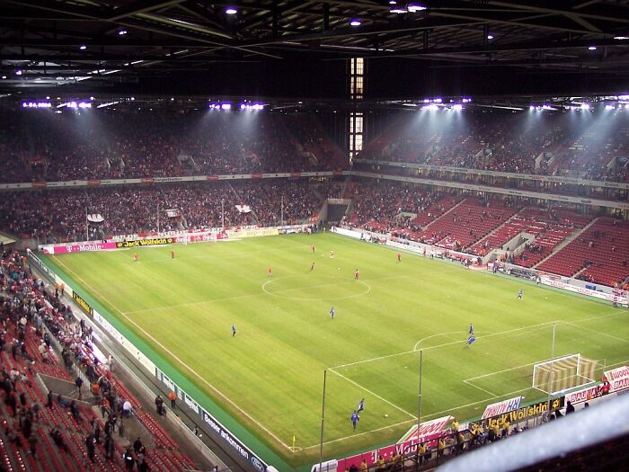 A large soccer stadium filled with fans under bright lights during an evening match in a famous cathedral of soccer.