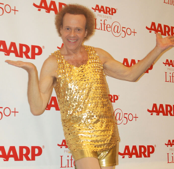 Celebrity in a gold outfit at an AARP event, posing for the camera.
