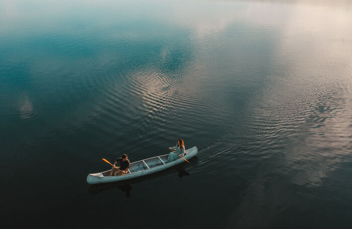 A couple in a canoe on a serene lake, showcasing one of the best engagement photos of 2025.