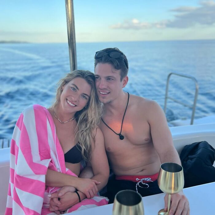 Couple enjoying a boat ride, wrapped in a striped towel, related to "Love Is Blind" contestant's views debate.