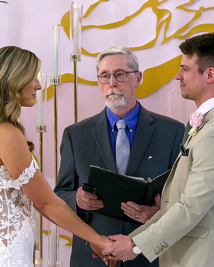 A couple holds hands with an officiant at a ceremony from "Love Is Blind.