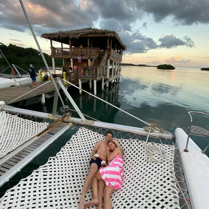 Couple relaxing on a boat hammock at sunset, sparking debate over love and conservative views.