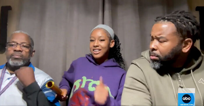 Young woman in purple hoodie shares video to support innocence, flanked by two men, in a news interview setting. Young woman in purple hoodie shares video to support innocence, flanked by two men, in a news interview setting.