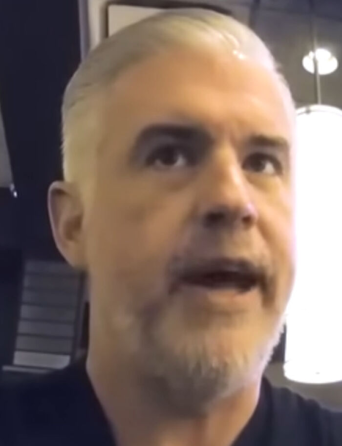 Man speaking indoors, related to State Farm executive controversy over LA wildfire remarks.