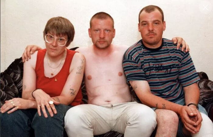 Three people sitting closely on a couch, each with tattoos, conveying seemingly normal yet possibly terrifying stories.