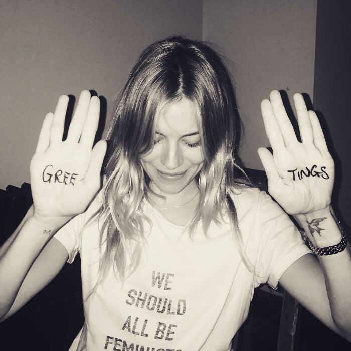 Woman in a "We Should All Be Feminists" shirt, raising hands marked "Greef" and "Tings," addressing baby at 42 criticism. Woman in a "We Should All Be Feminists" shirt, raising hands marked "Greef" and "Tings," addressing baby at 42 criticism.