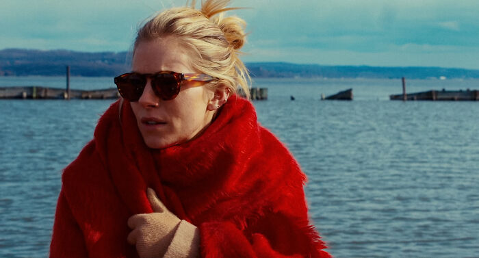 Sienna Miller in sunglasses and red coat by the water, responding to criticism about having a baby at 42. Sienna Miller in sunglasses and red coat by the water, responding to criticism about having a baby at 42.