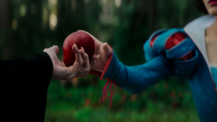 Snow White receives red apple, symbolic scene in Disney's film.