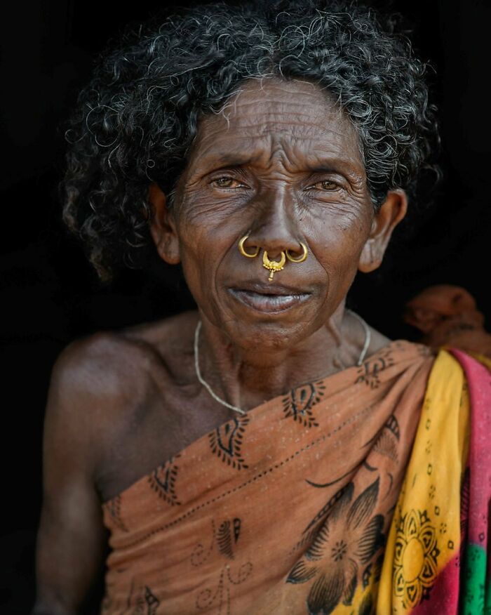 Elderly woman with curly hair and traditional jewelry showcasing cultural beauty.