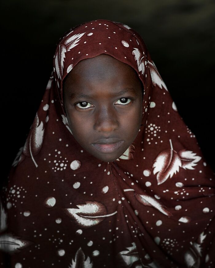 Young person in patterned maroon attire, showcasing cultural beauty worldwide.