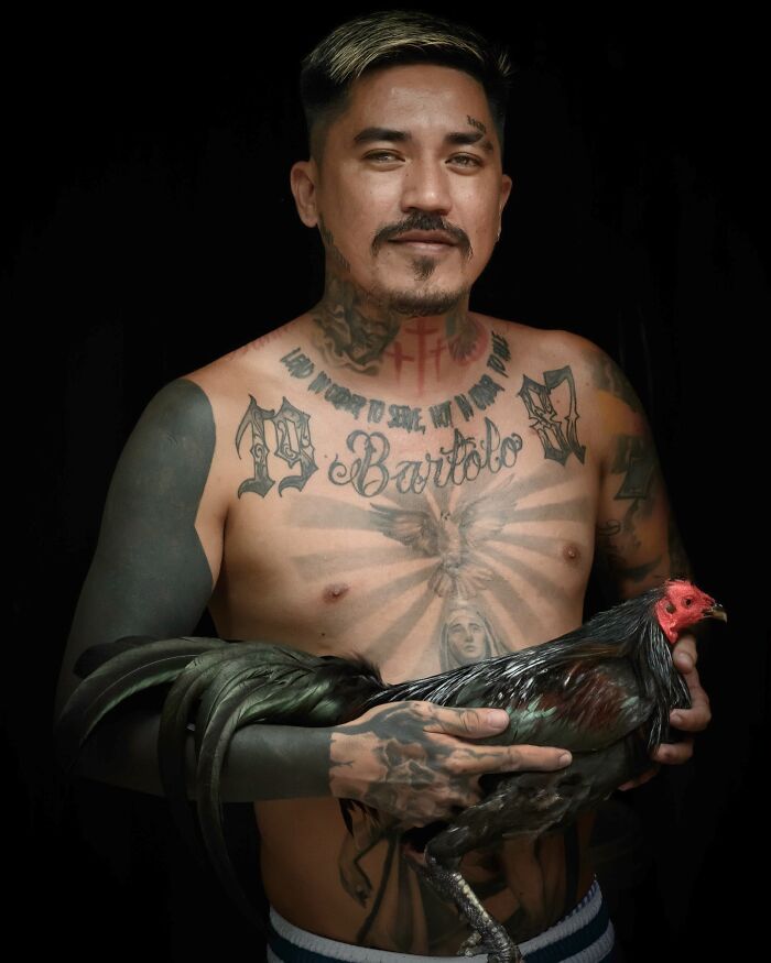 Man with tattoos holding a rooster, showcasing the beauty of cultures worldwide.