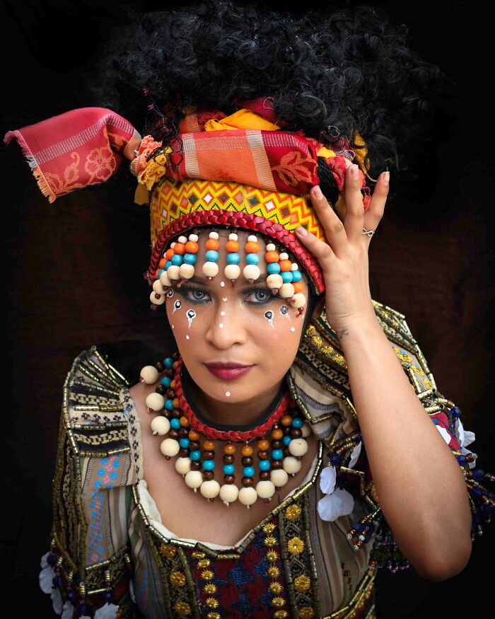 Woman in vibrant traditional attire with colorful beads and headscarf, showcasing cultural beauty.