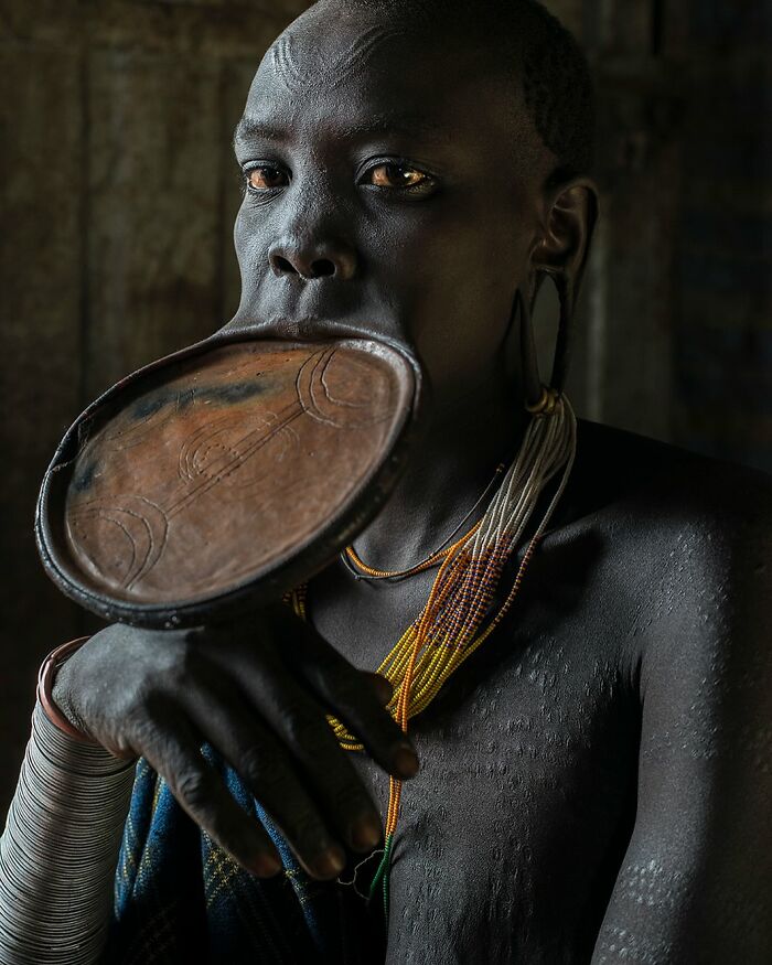 Individual from a diverse culture wearing large lip plate, showcasing beauty and tradition.