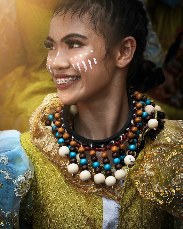 A person in colorful traditional attire and face paint, showcasing cultural beauty with a joyful expression.