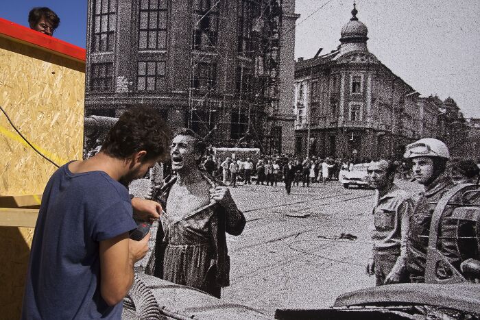 Man working on a large monochrome street photo mural, creating a blend of history and modern street photography.