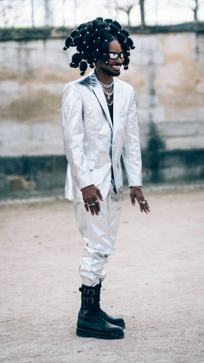 Striking street portrait of a person in a silver suit and unique hairstyle, showcasing bold fashion.