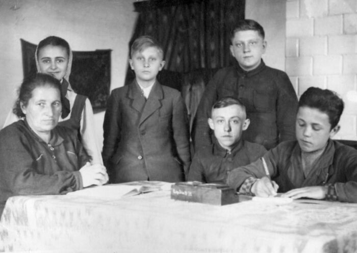 Historical turning point group portrait, people seated and standing around a table, vintage attire, black and white.