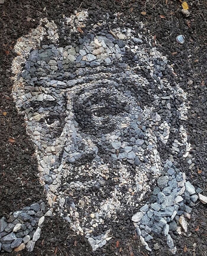 Intricate temporary mosaic of a man's face made with stones and pebbles by British artist.