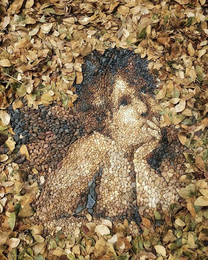 Intricate temporary mosaic of a cherub made from stones and pebbles, surrounded by dried leaves.