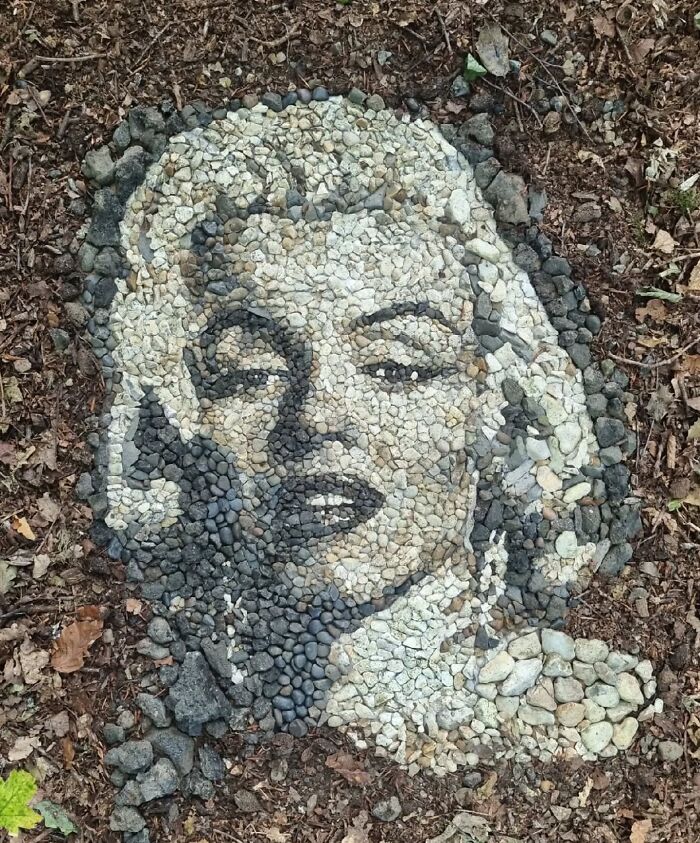 Pebble mosaic portrait on the ground created by a British artist, featuring intricate stonework in natural tones.